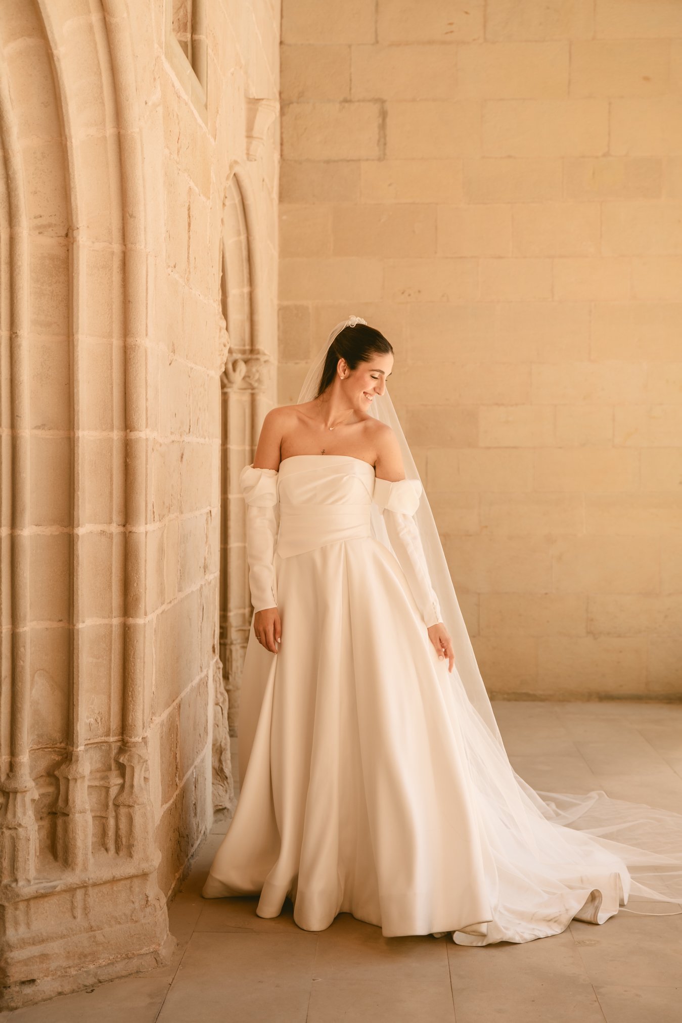 Novia posando sola frente a pared clásica de piedra