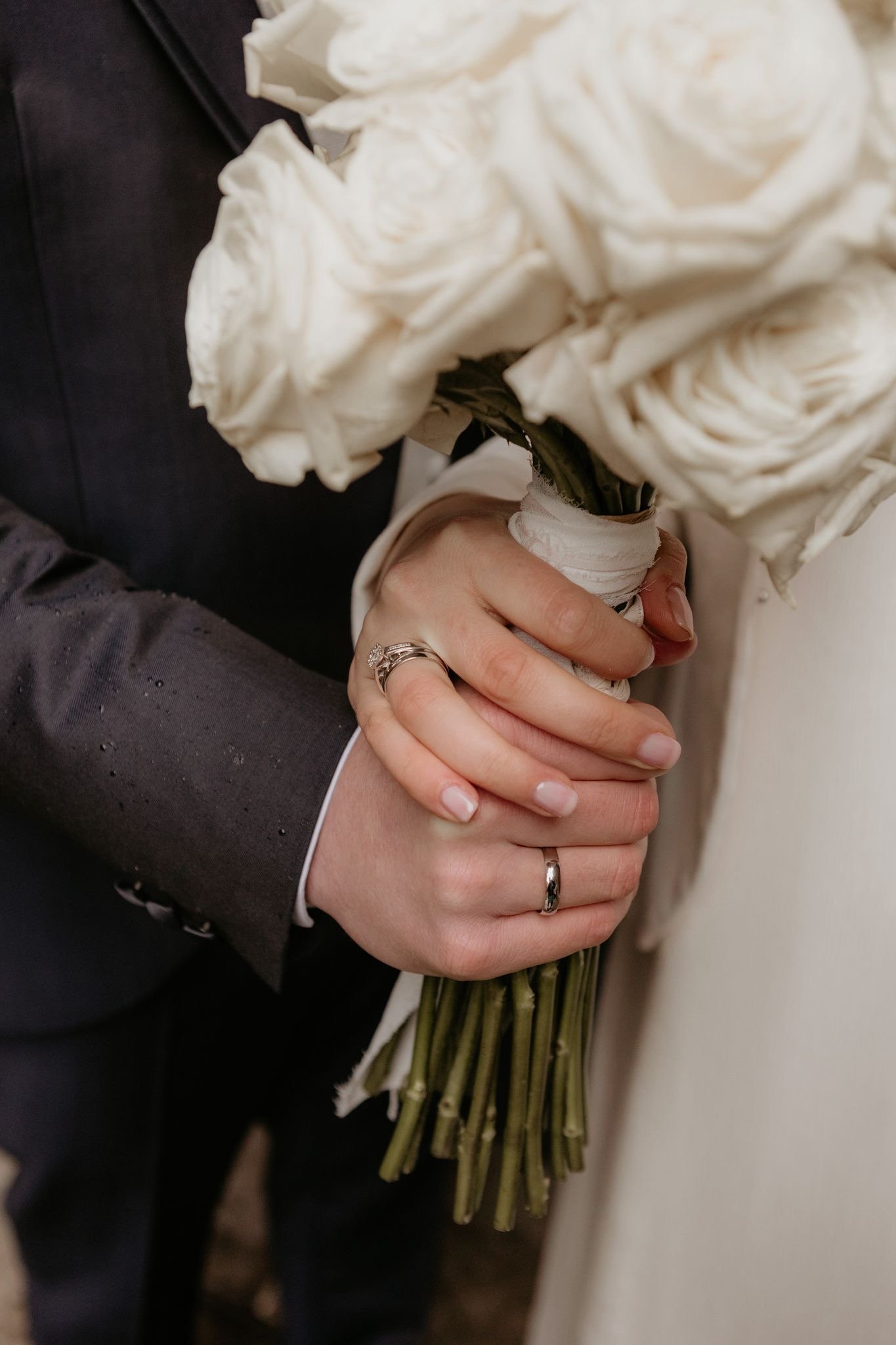 Primer plano de manos entrelazadas con ramo blanco