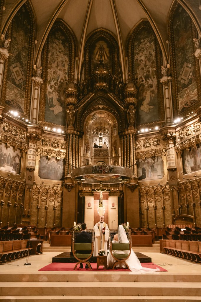 Novios posando en centro de iglesia dorada y monumental