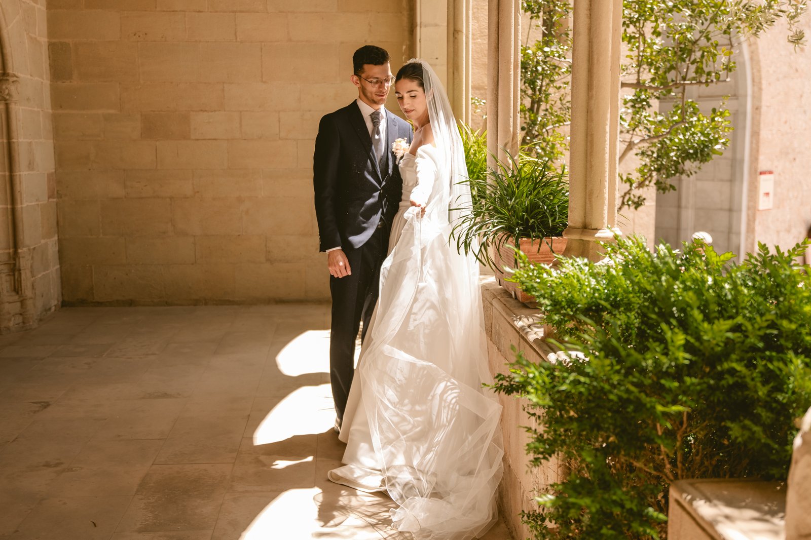 Novios bajando escalinata exterior con pétalos blancos
